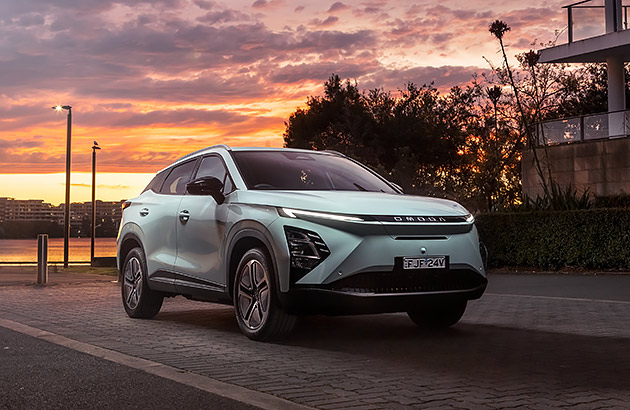 A mint green Chery Omoda  parked near a river at sunset