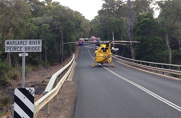 An RAC Rescue helicopter has landed on a road with a crash scene up ahead