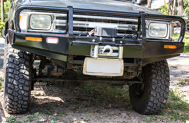 A close up of the front of a four-wheel drive on a gravel road