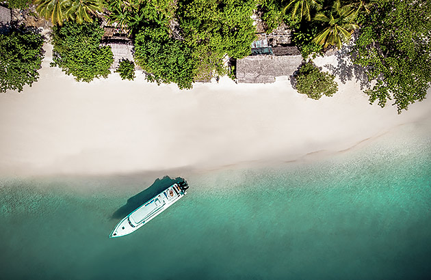 An aerial view of a boat on a white sand beach
