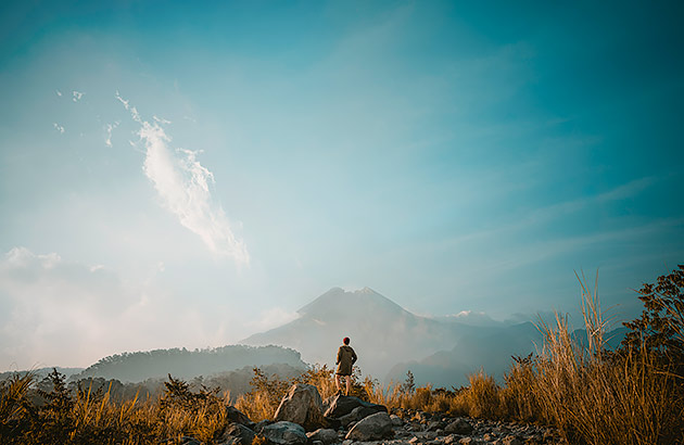 A man looking towards a volcano in the distance
