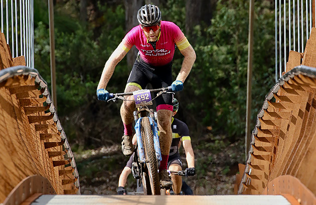 A mountain bike rider coming over the suspension bridge in Dwellingup