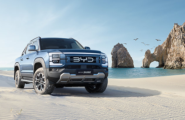 A blue BYD shark ute on a white sand beach