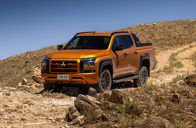 An orange Mitsubishi Triton on a rocky hillside