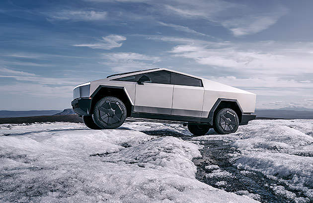 A white Tesla Cybertruck driving on a snow an ice-covered landscape