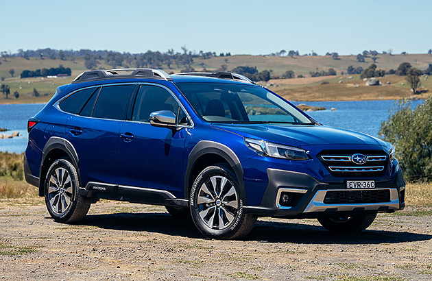 A blue Subaru Outback XT parked in a rural setting