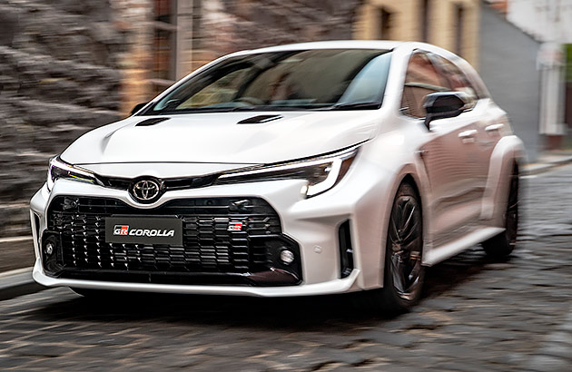 A white Toyota GR Corolla in a narrow city street