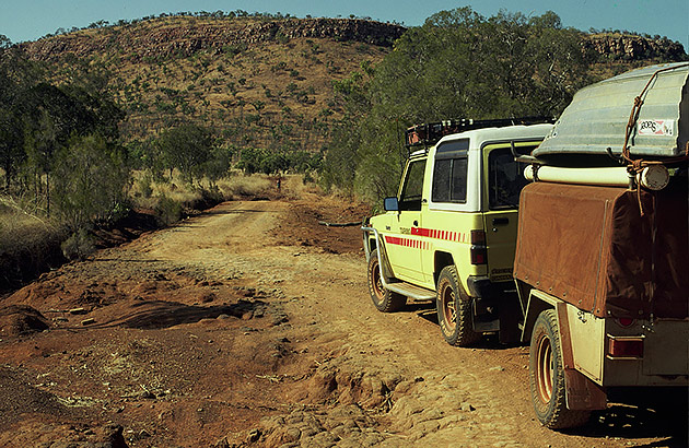 A four-wheel drive towing a camper trailer on a dirt track