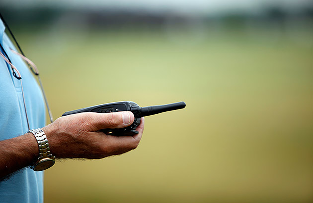 A close-up of a man holding a handheld UHF radio