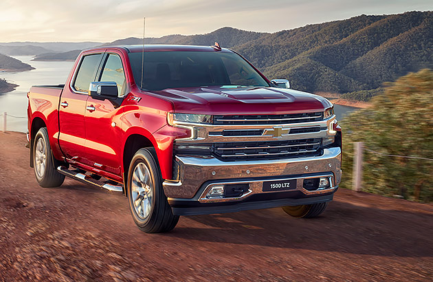 A red Chevrolet Silverado on a dirt road with hills in the distance