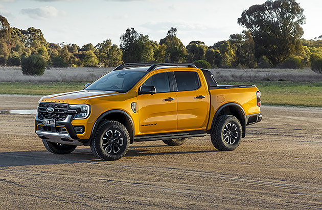 A gold Ford Ranger parked on a dirt road in a rural setting