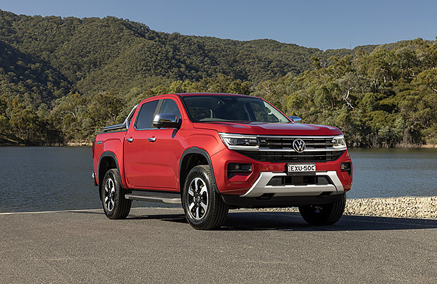 A red Volkswagen Amarok parked by a lake