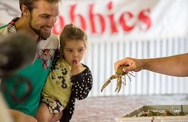 A man holding a child as they both look at a yabbie