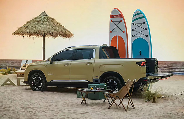 A mustard yellow Geely Ridara parked on a beach near stand-up paddle boards