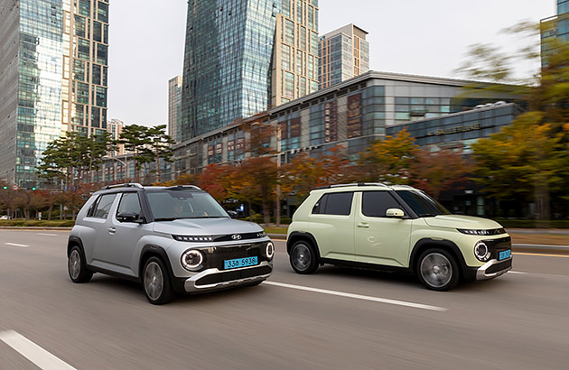 Two Hyundai Inster EVs driving on a city street