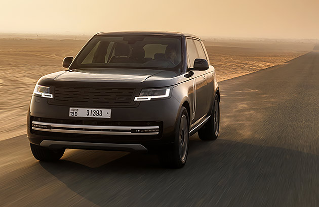 A black Range Rover EV driving on a dusty country road