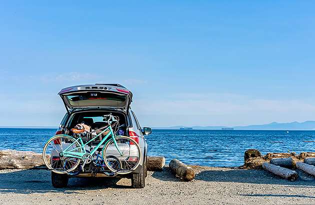 A car parked at the beach with a bike rack covering the number plate