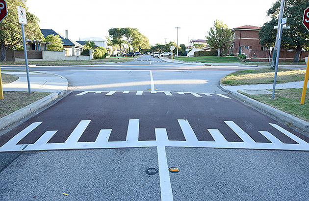 A speed hump on a suburban road with piano markings on its edge