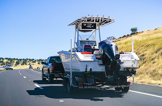 A car towing a large boat on a regional road