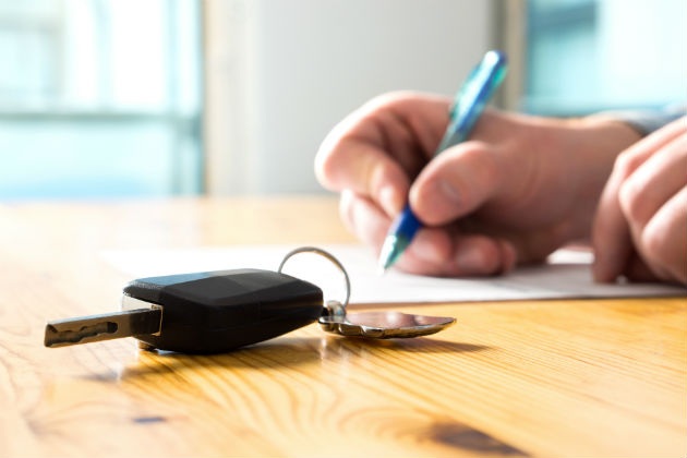 A key on a table where someone is signing a paper