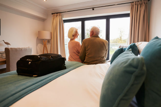 Couple sitting on a bed with a suitcase