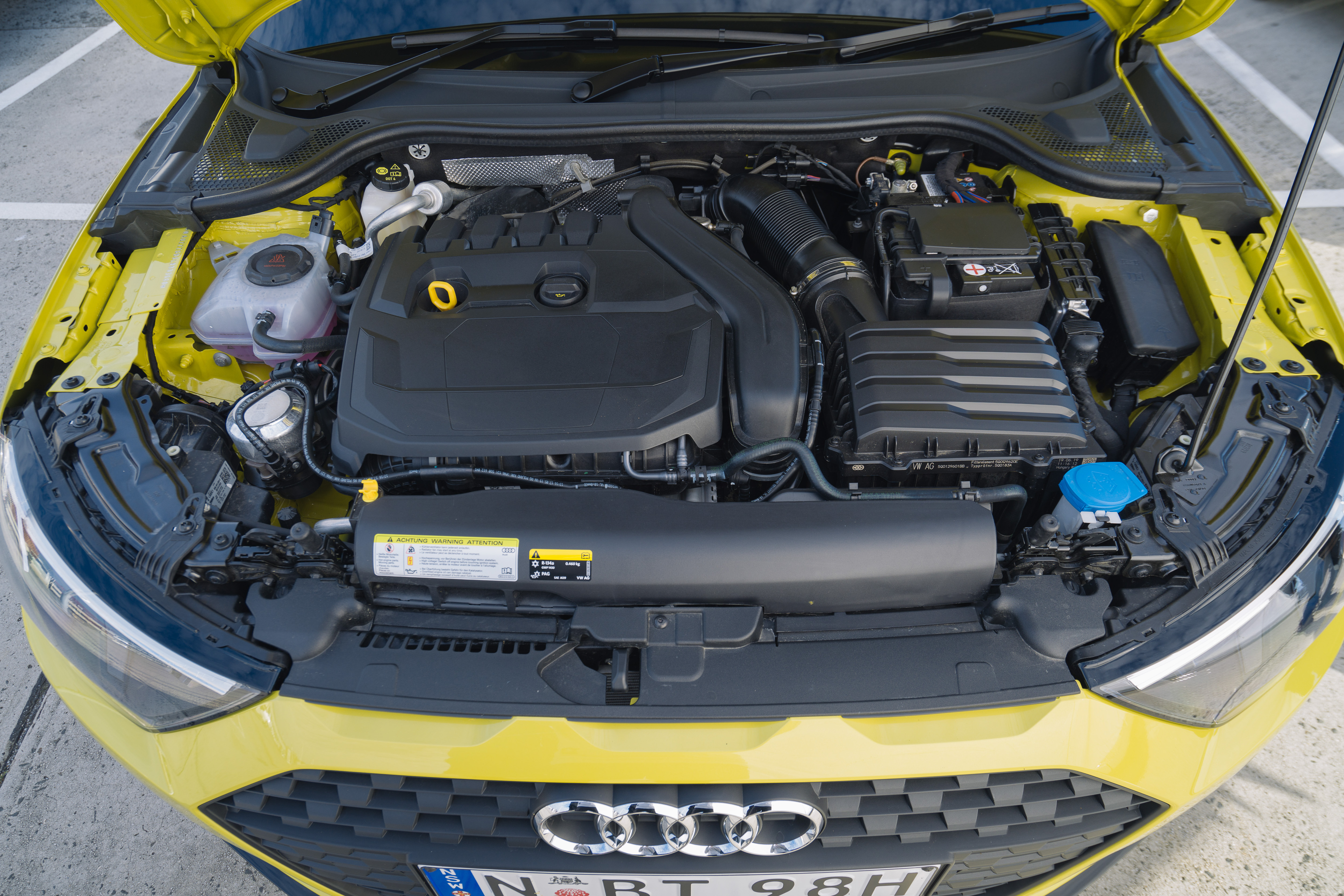 Open front bonnet of yellow Audi A1 to show turbo engine