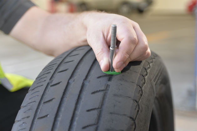 A tyre technician checking the tread of a bald tyre