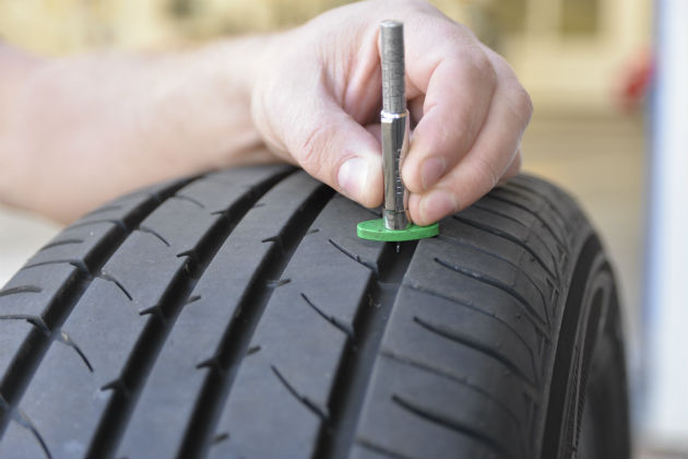 A tyre technician checking the tread of a full tyre