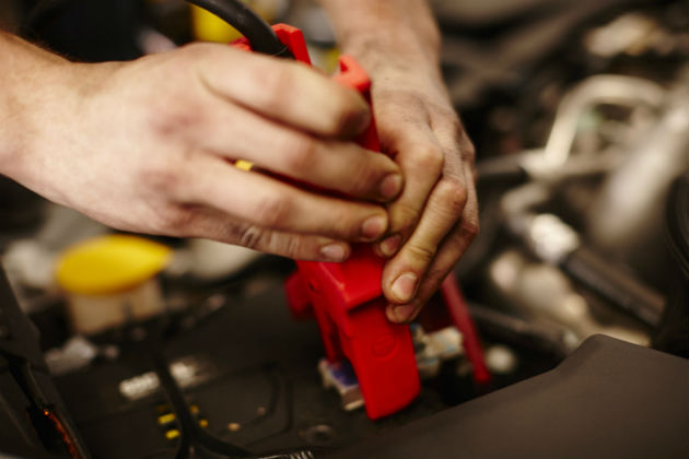 A mechanic jump-starting a car with a flat battery