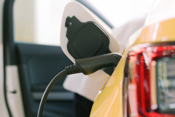 Closeup of an electric vehicle's charging connector as it charges a yellow car