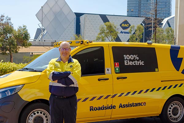 An RAC Roadside Assistance mechanic stands in front of a yellow RAC van
