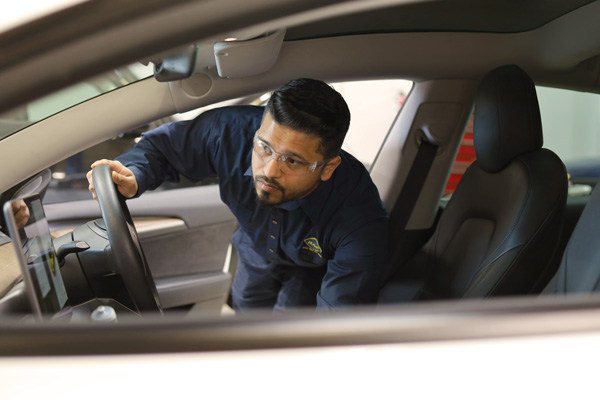 An RAC Auto Service mechanic performing an inspection on a used vehicle