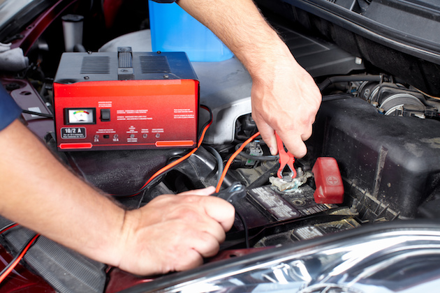 Image of man using a battery charger on car