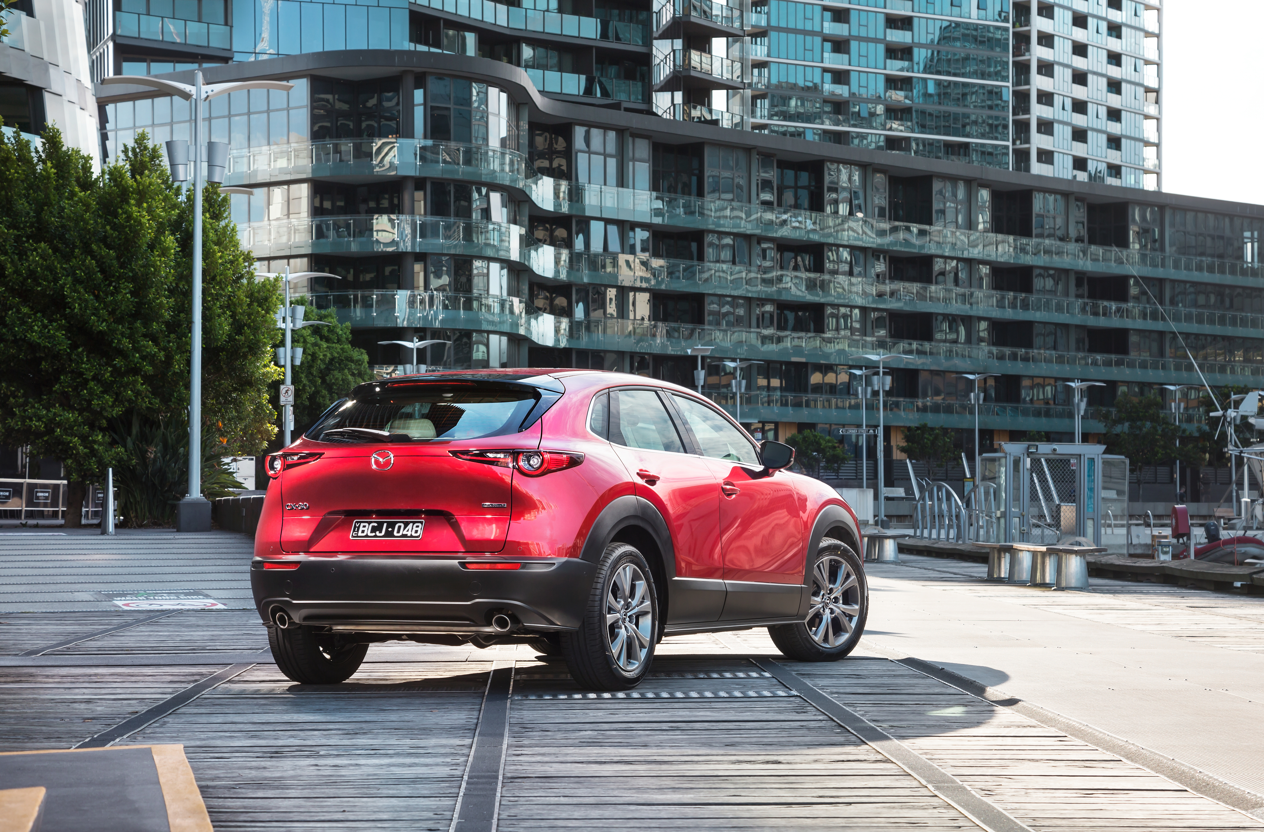 Red Mazda CX30 in front of tall apartment buildings