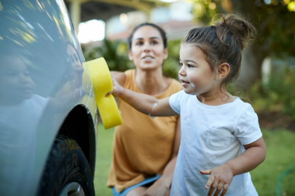 Parent and child washing car in drive way