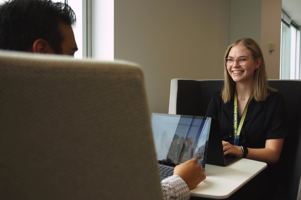 An RAC employee is sitting in front of her colleague with an open laptop