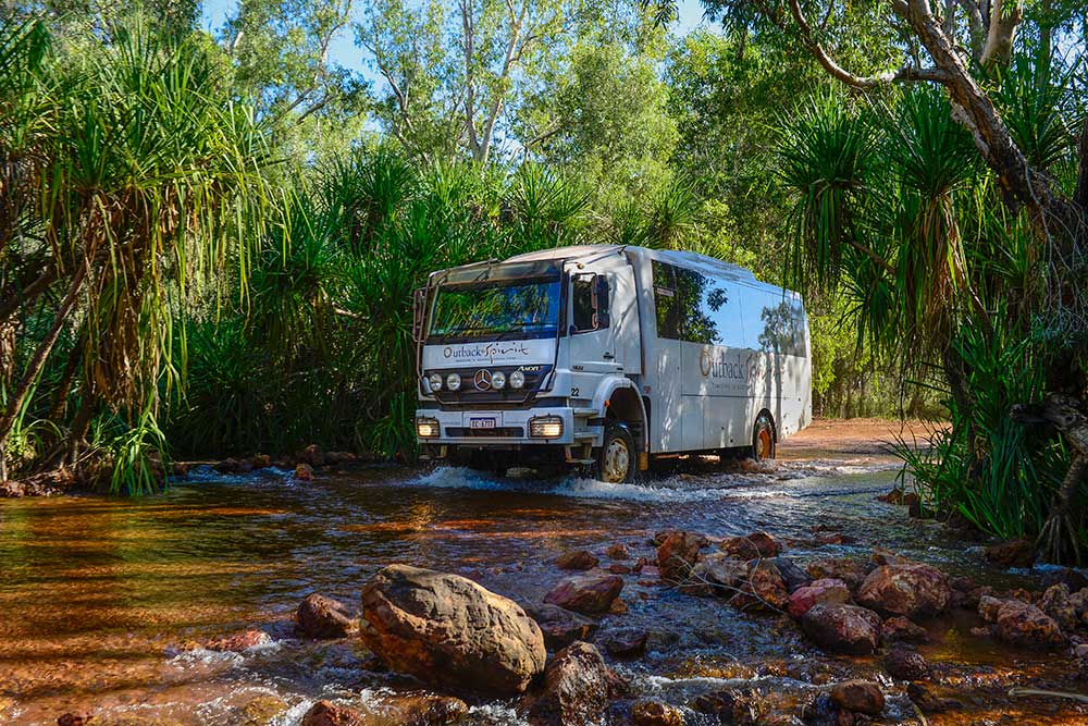 An adventure bus travels through a shallow creek in Arnhem Land