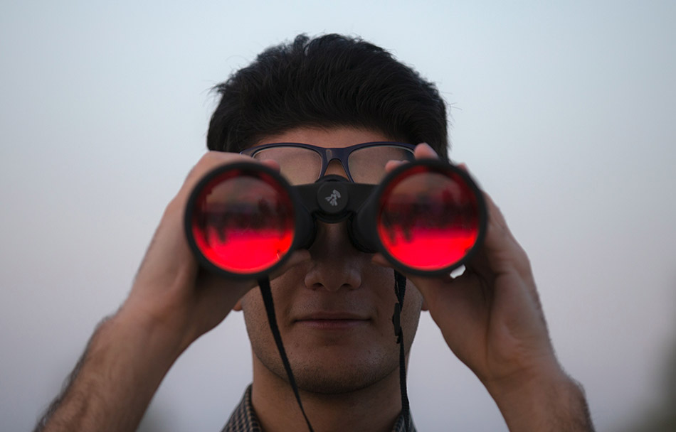 A man is looking through a set of binoculars