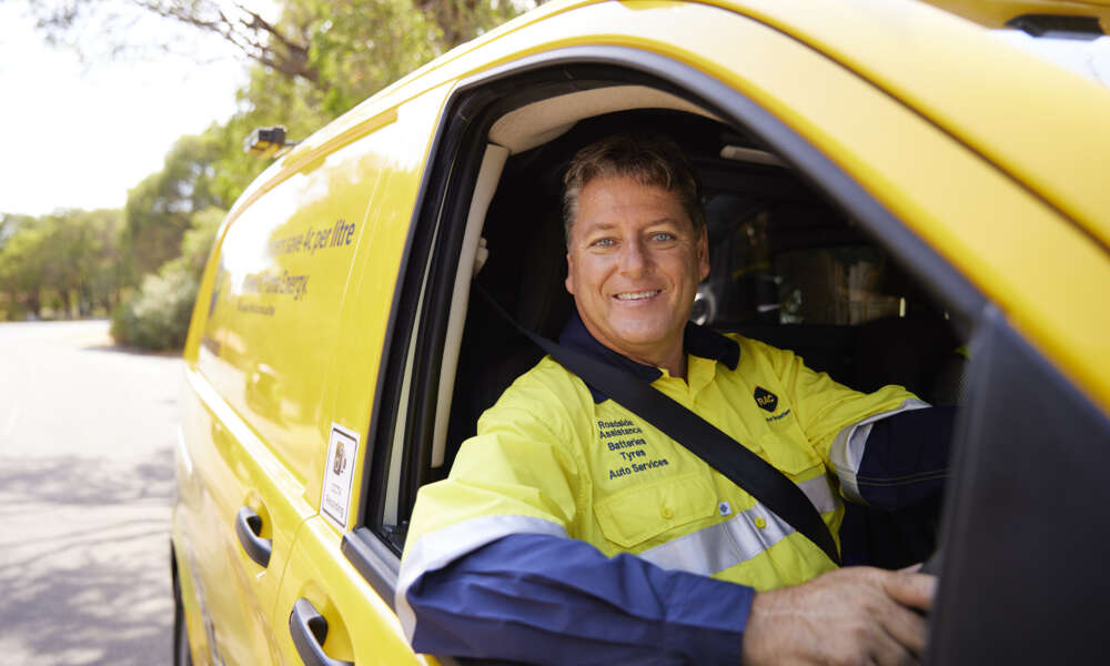 An RAC roadside patrol driver is sitting in his parked vehicle smiling