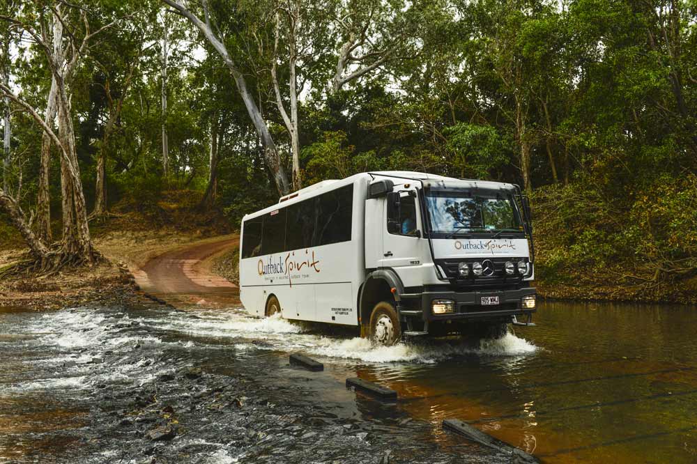 An Outback Spirit coach traveling over an outback road covered in water