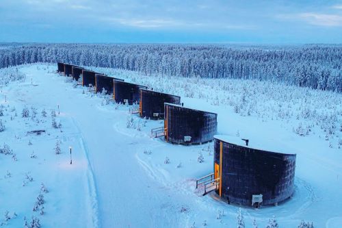 Aerial view of the Livo Arctic Resort with its multiple huts surrounded by snowy forest 