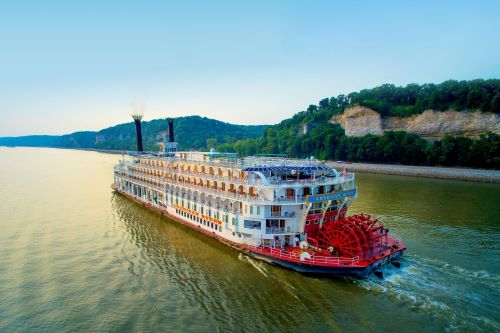 American Queen steamboat with its red paddlewheel cruising down the river