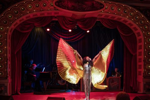 The main stage aboard the American Queen with a singer dressed in a gold costume with wings that she is spreading while singing. 