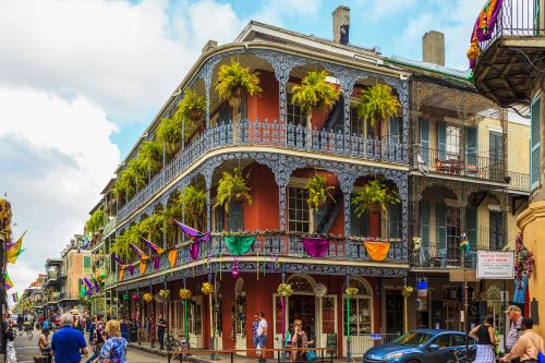 A colourful historic building with beautiful balcony railings and lots of hanging plants in the French Quarters of New Orleans