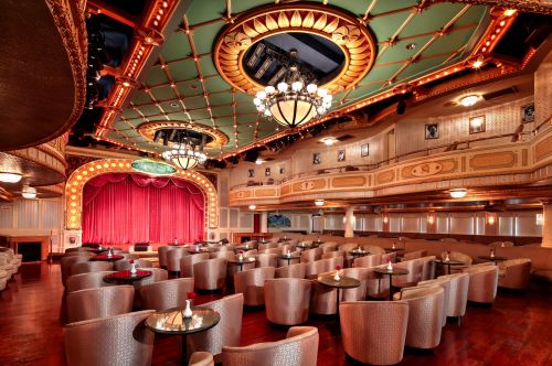 The theatre aboard American Queen which resembles a 19th-century opera house with a red curtain in front of the stage and massive chandeliers hanging off the ceiling