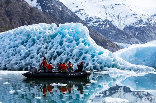 A tender boat with some people cruising in between iceberg formations 