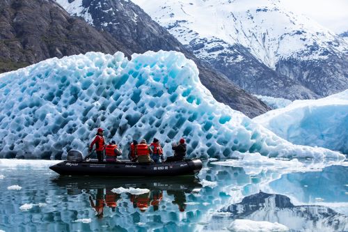 A tender boat with some people cruising in between iceberg formations