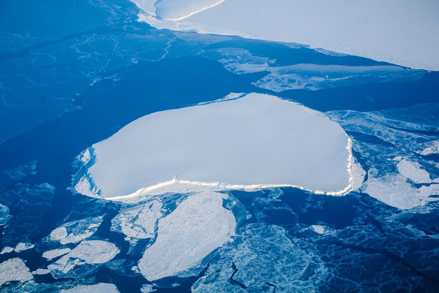 Aerial view of sea ice which is floating on the dark blue ocean