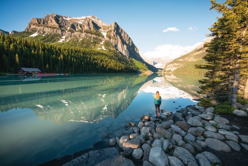 Clear emerald waters of Lake Louise reflecting the surrounding mountain landscape on a sunny day