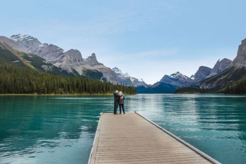 A couple standing at the end of a jetty at Lake Loise with mountains in the background